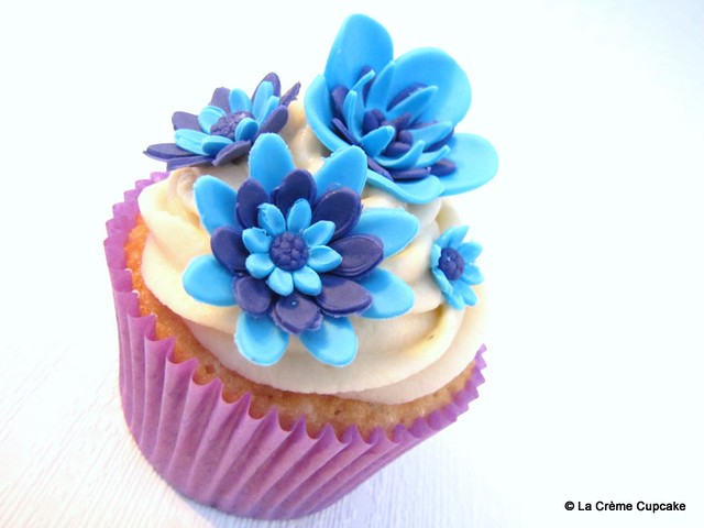 Vanilla cupcake decorated with striking electric blue and purple flowers