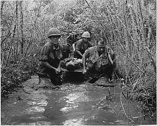 Soldiers carry a wounded comrade through a swampy area, 1969.