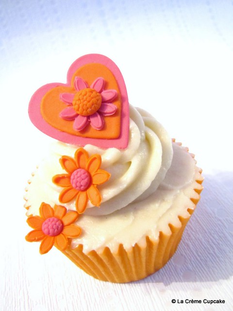 Vanilla cupcake decorated with orange and pink hearts and flowers