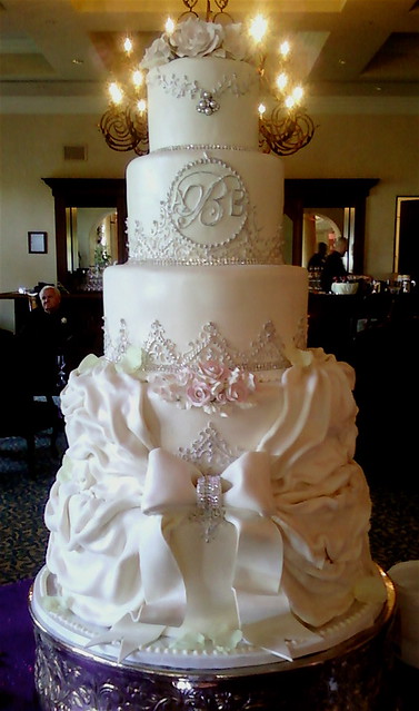 Tiered wedding cake with Victorian design featuring a big bow tying fondant 