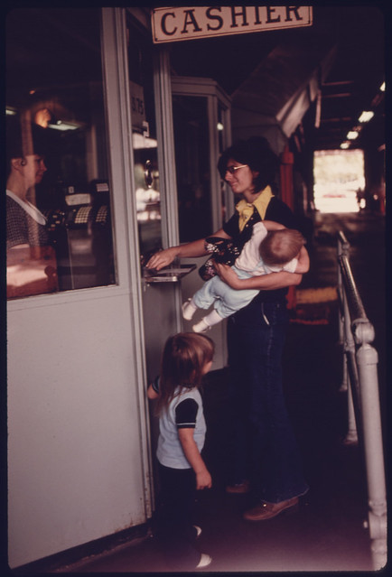 Mother with Her Children at the Cashier's Window Paying for Her Annual Sticker after Her Car Had Successfully Passed Testing at an Auto Emission Inspection Station in Downtown Cincinnati, Ohio...09/1975