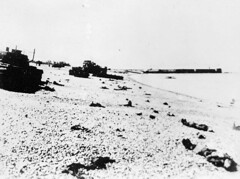 Canadian dead litter the Dieppe beach among ruined and abandoned tanks. / Les corps de soldats canadiens sur la plage de Dieppe entouré par des chars d'assaut abandonnés et détruits