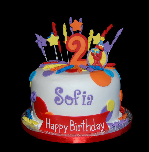 Red orange yellow blue and purple 2nd birthday cake with Elmo candle