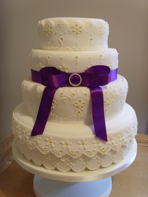 A four tier ivory wedding cake decorated in Broderie Anglaise style 
