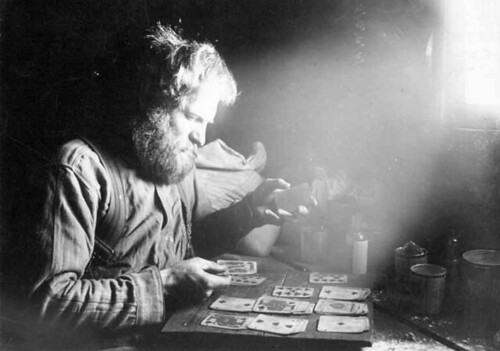 Charles Ainsworth playing cards inside cabin at 60 Above on Sulphur Creek, Yukon Territory