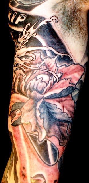 A red peony tattooed on the inside of an arm
