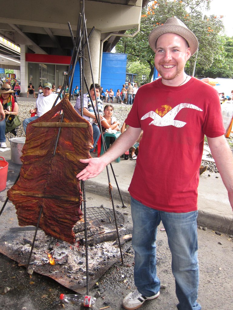 A large slab of meat cooks on the street.