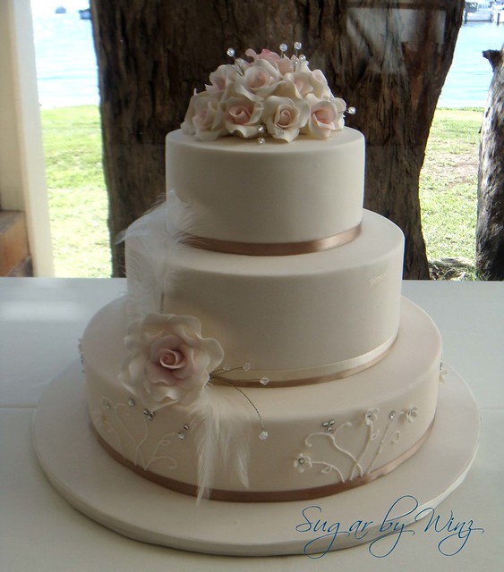 Romantic wedding cake with roses and feathers The bride wore feathers in