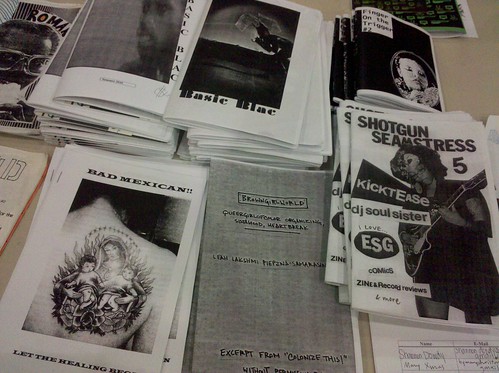a table with a smattering of zines made by people of color, including shotgun seamstress by osa atoe