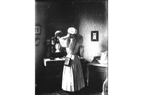 Unidentified woman trying on hat in front of mirror, Washington