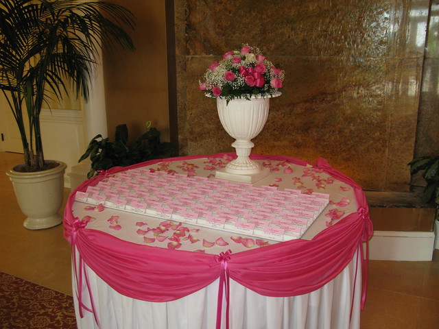 Place card table adorned with elegant pink fabric swags and florals for a