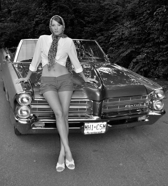 black & white photo of a 1965 Pontaic Convertiable with a girl leaning on the hood