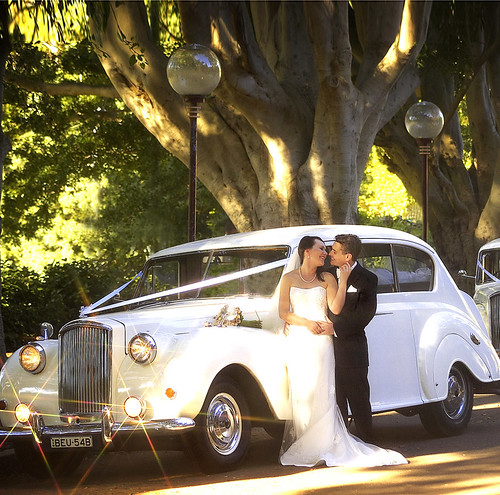 The bride and groom in-front of a Princess car.