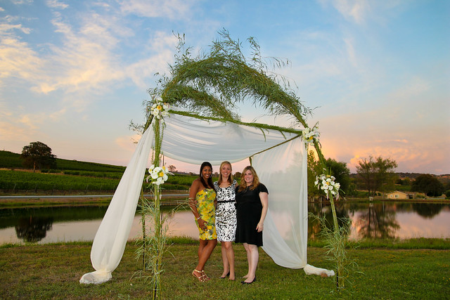 A few friends stop for a picture under a wedding trellis at sunset