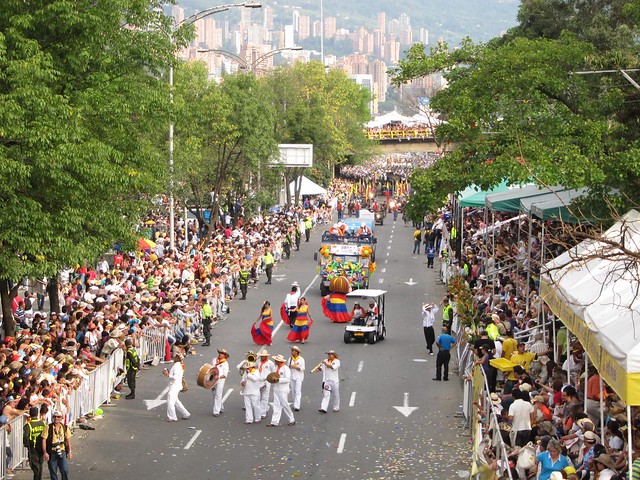 A marching band and women wearing the colors of the Colombian flag.