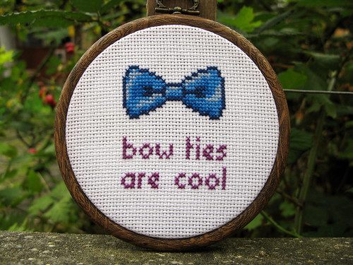 A cross-stitched pattern of a blue bow tie, below it in red letters it says BOW TIES ARE COOL