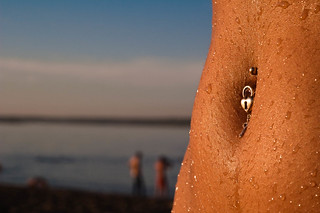 Girl's belly and the beach. Piercing jewelry