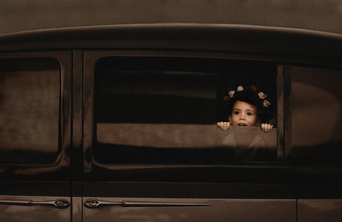 Flowergirl playing in vintage car.