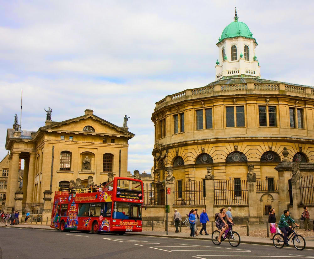 A City Sightseeing Oxford tour bus sets down passengers in Broad Street, Oxford, between the Clarendon Building on the left and the Sheldonian Theatre on the right. Credit Martin Addison