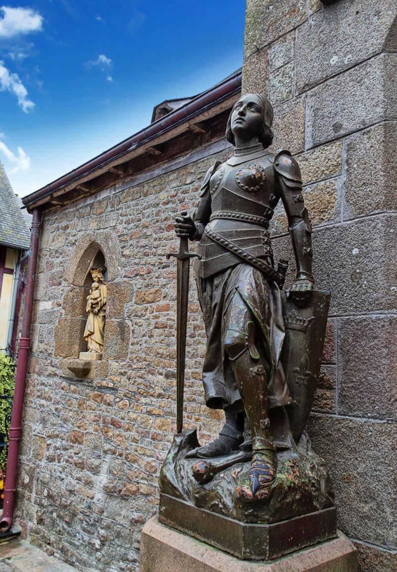 Statue of Joan of Arc next to the transept door of the Saint-Pierre church of Mont-Saint-Michel, Manche, France. Credit EdouardHue