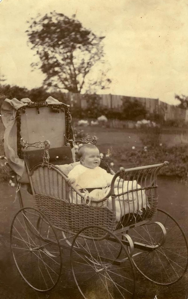 1914. Baby Charmain, aged 7 months seated in an elaborate cane pram