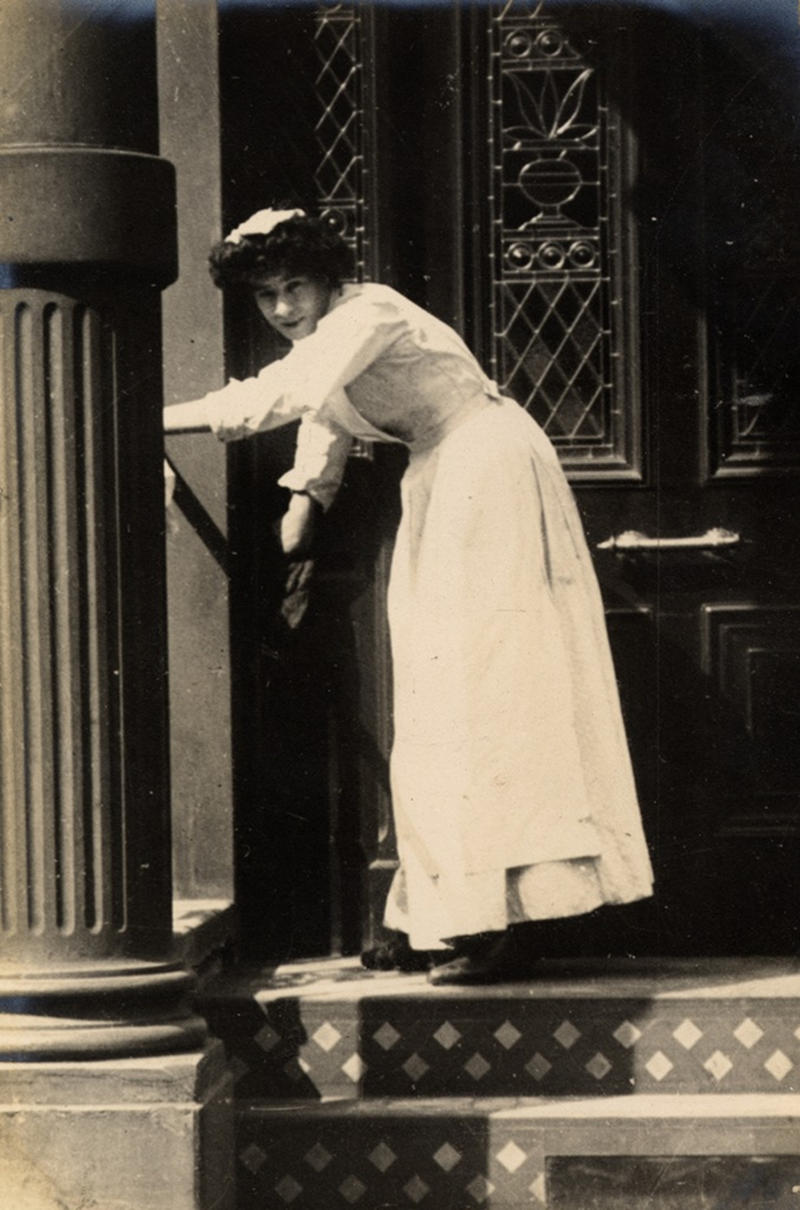 One step at a time. The tedious job of cleaning the porch steps, 1906