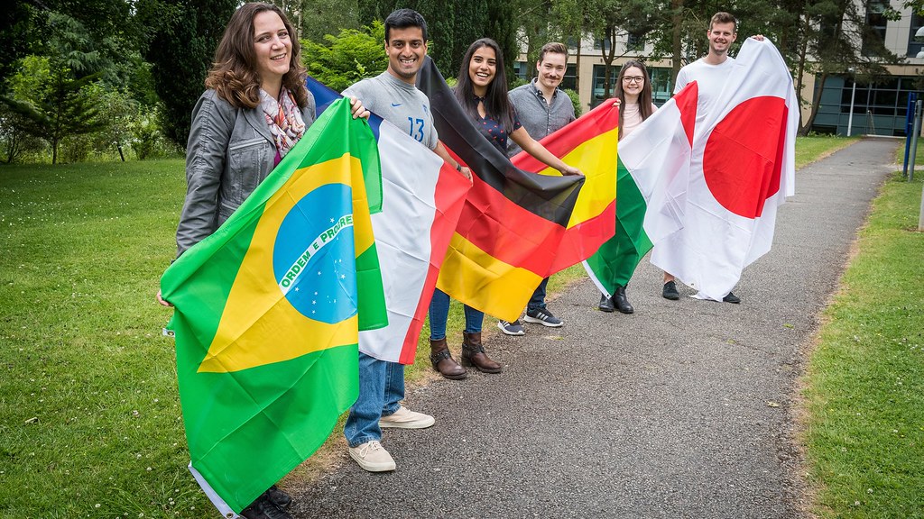 六名学生分别举着葡萄牙、法国、德国、西班牙、意大利和日本的国旗.