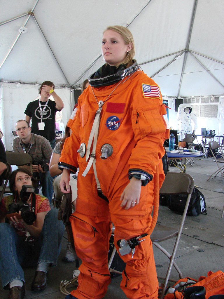 Надеть скафандры. Зена Нордман астронавт. Оранжевый скафандр. Оранжевый космический костюм. Космонавт в оранжевом костюме.