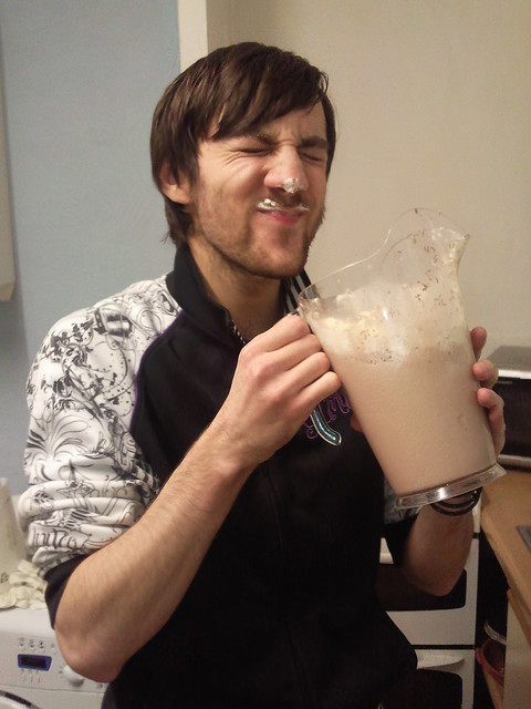 Man holding a pitcher of milkshake with a milkshake mustache on his lip