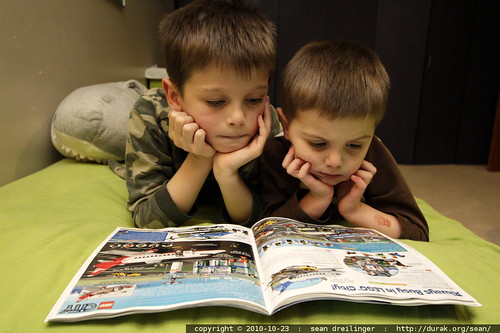 brothers poring over a lego catalog that arrived in today's mail