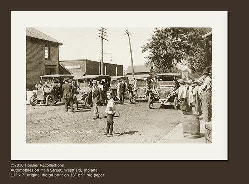people usa signs man men history cars boys kids buildings walking advertising children awning clothing general crowd hats indiana streetscene flags celebration transportation shops pedestrians storefronts grocery westfield automobiles businesses realphoto hoosierrecollections