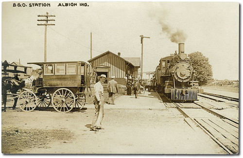 horses people woman usa man men history station sepia buildings walking clothing dock women workmen hats indiana trains transportation depot hotels businesses railroads albion wagons realphoto hoosierrecollections