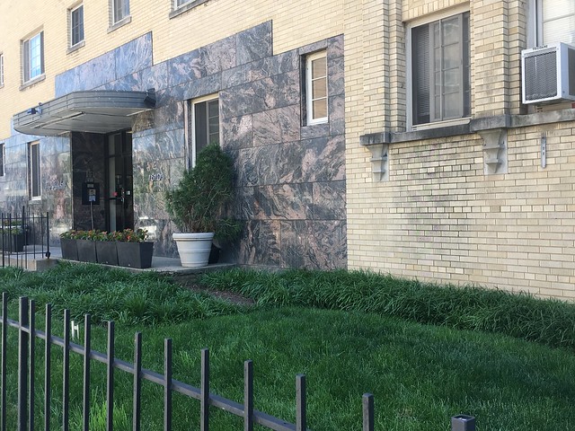 Image of the front of an Parkhill Apartment building. In front of the apartment is fenced in grass that is well groomed and looks healthy. 