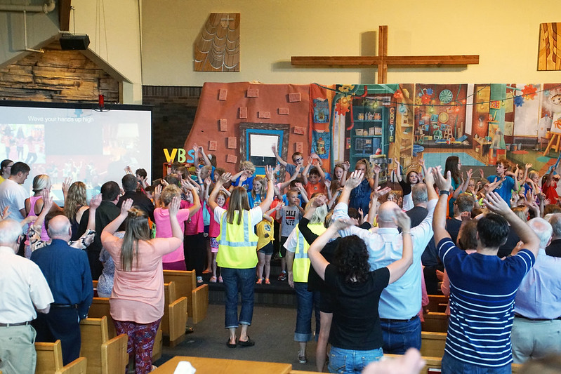 A congregation standing up and raising both arms while in church