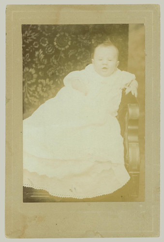 Card mounted portrait of baby in smock