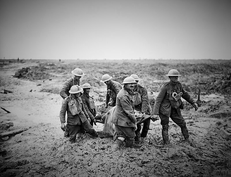 Stretcher bearers struggle in mud up to their knees to carry a wounded man to safety