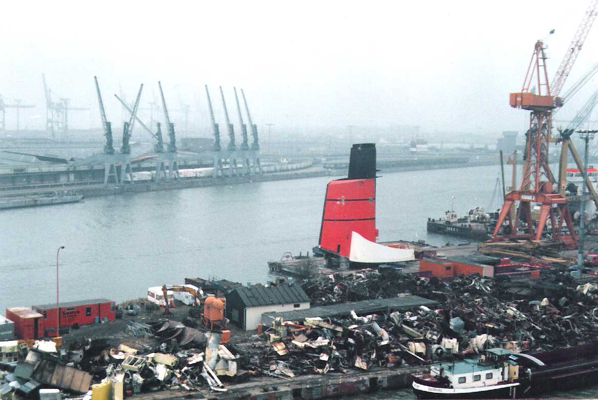 Images of the QE2's 1987 re-engining and refit in Bremerhaven, Germany. In the bottom photo, the ship's original funnel is shown lying on the quayside; her old fixed-pitch propellers are lying to the bottom left hand side of the photo.