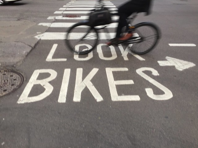 "Look bikes" painted on pavement with a bicycle passing over it
