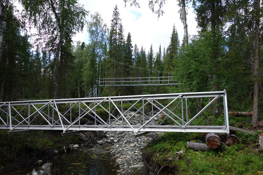 Temporary bridge across a side stream of Vállejåhkå in the foreground. New bridge replacing the destroyed one in the background.