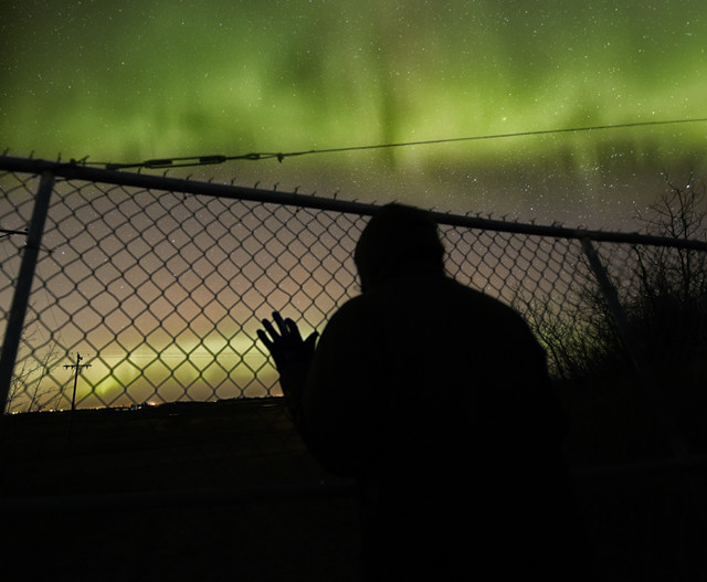 Northern lights through a fence