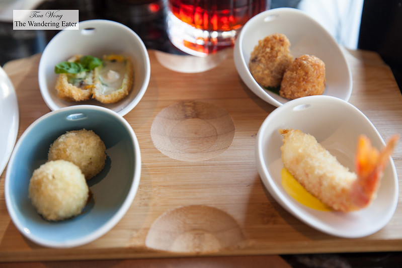 Selection of four cicchetti - Fried courgette blossom stuffed with mozzarella and anchovies; fried and stuffed rice ball, Roman style; crunchy prawn; fried and stuffed rice ball with tomato dip