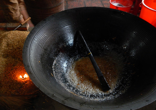 Making caramel over a fire fuelled by rice husks at the snack factory on the Mekong River in Vietnam