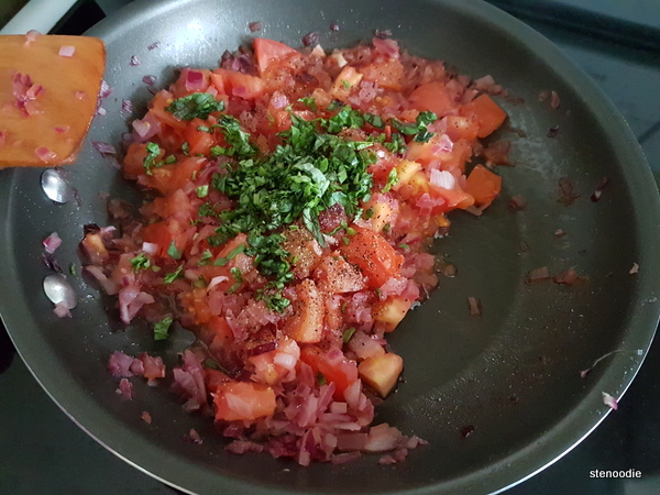 red onion and tomatoes cooking in pan