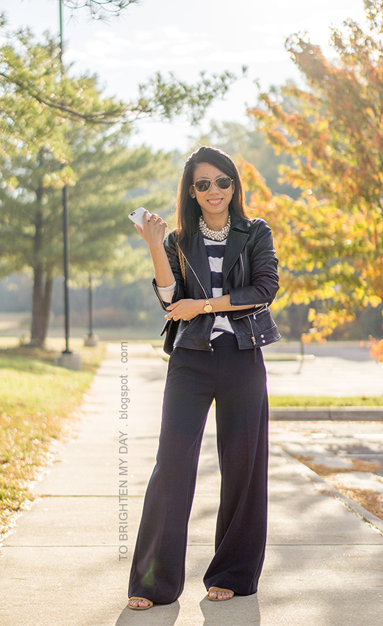 black leather jacket, pearlized necklace, navy and white striped top, gold watch, navy wide legged pants, black shoulder bag, brown suede flats