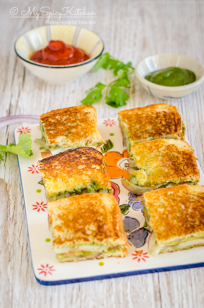Bombay Grilled Vegetable Sandwich is a street food from Mumbai India.  Spicy green chutney is the spread and potato onion cucumber tomatoes are used to make the sandwich. 