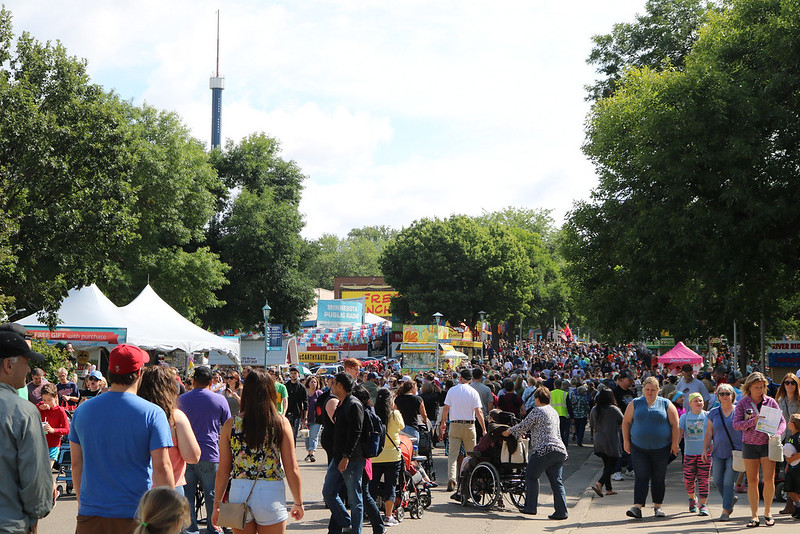 one of the streets at the fairgrounds, packed with people, with the space needle in the distance