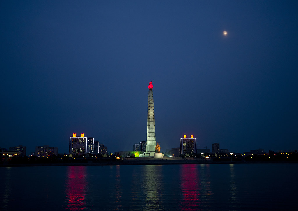 Juche tower with red flame in front of the Taedong river at night, Pyongan Province, Pyongyang, North Korea
