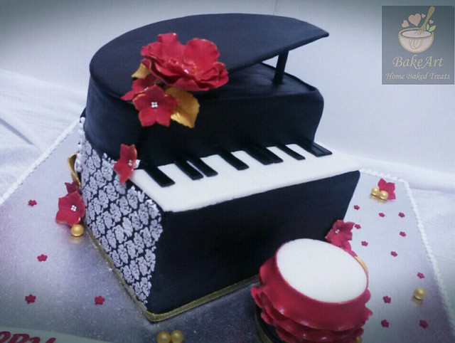 Piano Cake. The cake is decorated with my BakeArt homemade Fondant, Stenciled with Royal icing on either sides of the piano, Created Lovely red Sugar flowers and Gold leaves with some fondant made gold pearl