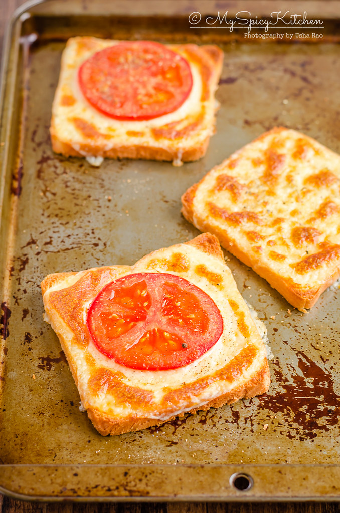 A slice of cheese toast and two slices of 3 ingredient tomato cheese toasts on a baking sheet