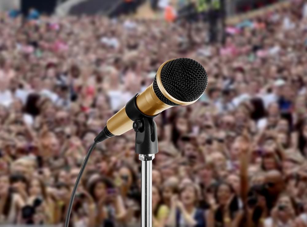 Closeup of microphone with large audience in background